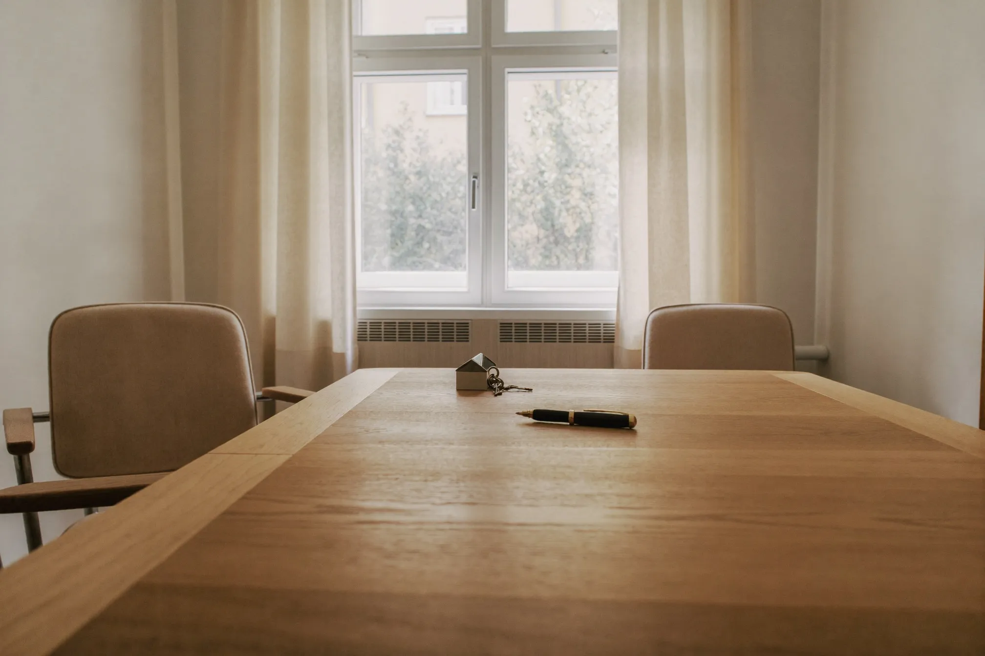 Heller Besprechungsraum mit Holztisch, Stühlen und Tageslicht.